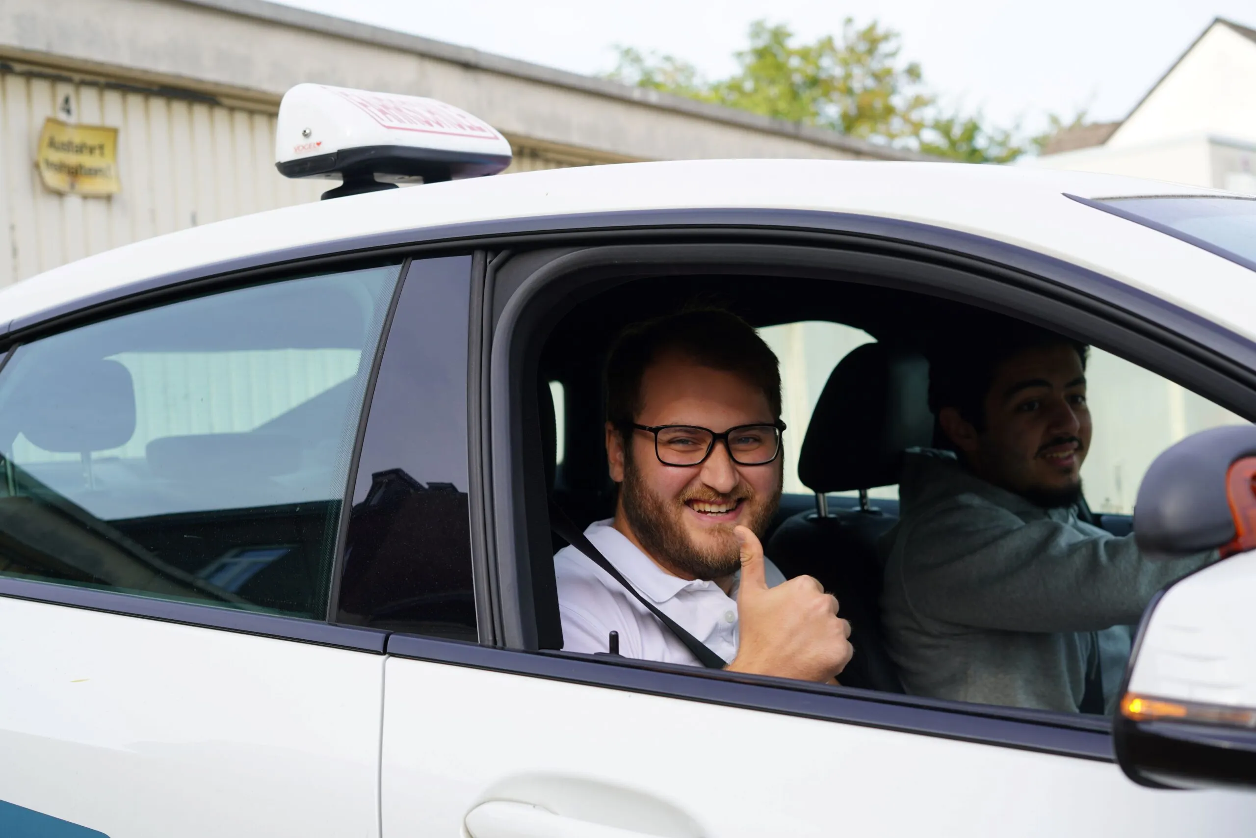 Fahrlehrer der 123fahrschule sitzt in einem Fahrschulauto und zeigt den Daumen nach oben