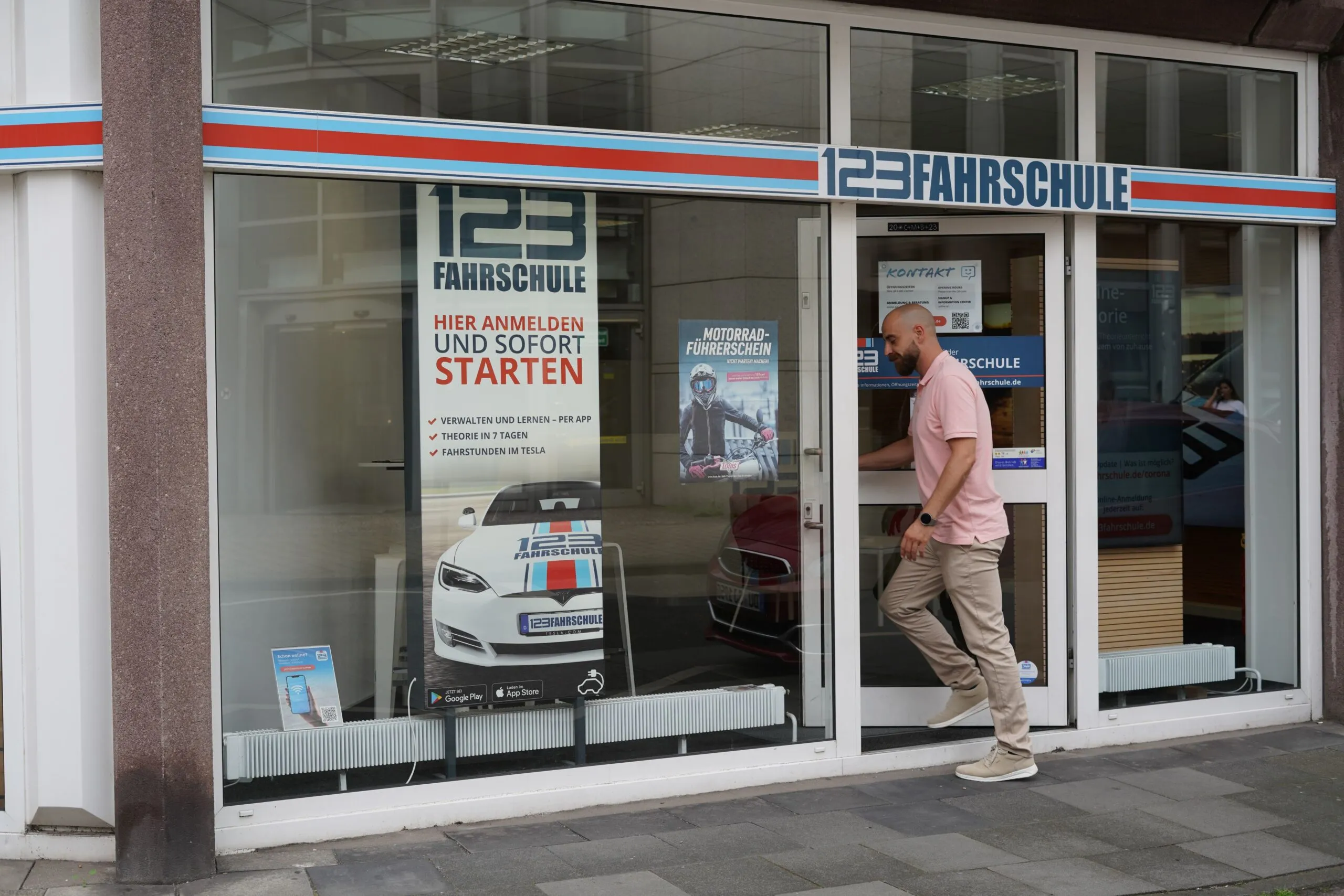 Ein Fahrlehrer der 123 Fahrschule geht durch die Tür in eine 123 Fahrschule-Filiale