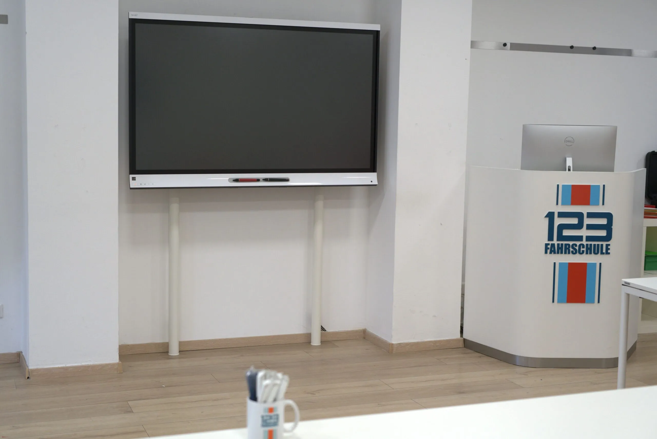 Filiale einer Fahrschule von innen mit einem Bildschirm an der Wand