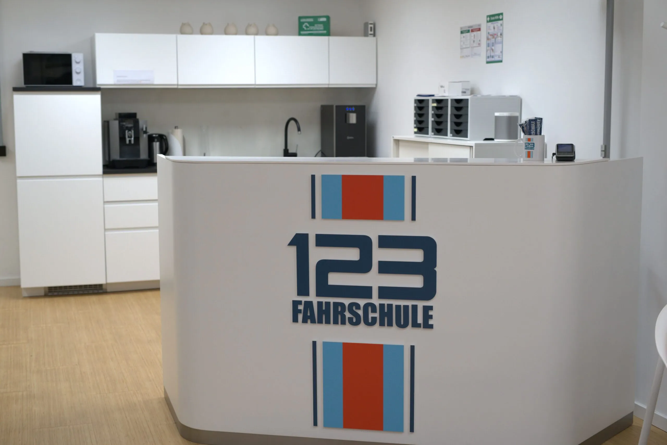weiße Küche und Rezeption mit Werbeaufschrift der 123Fahrschule