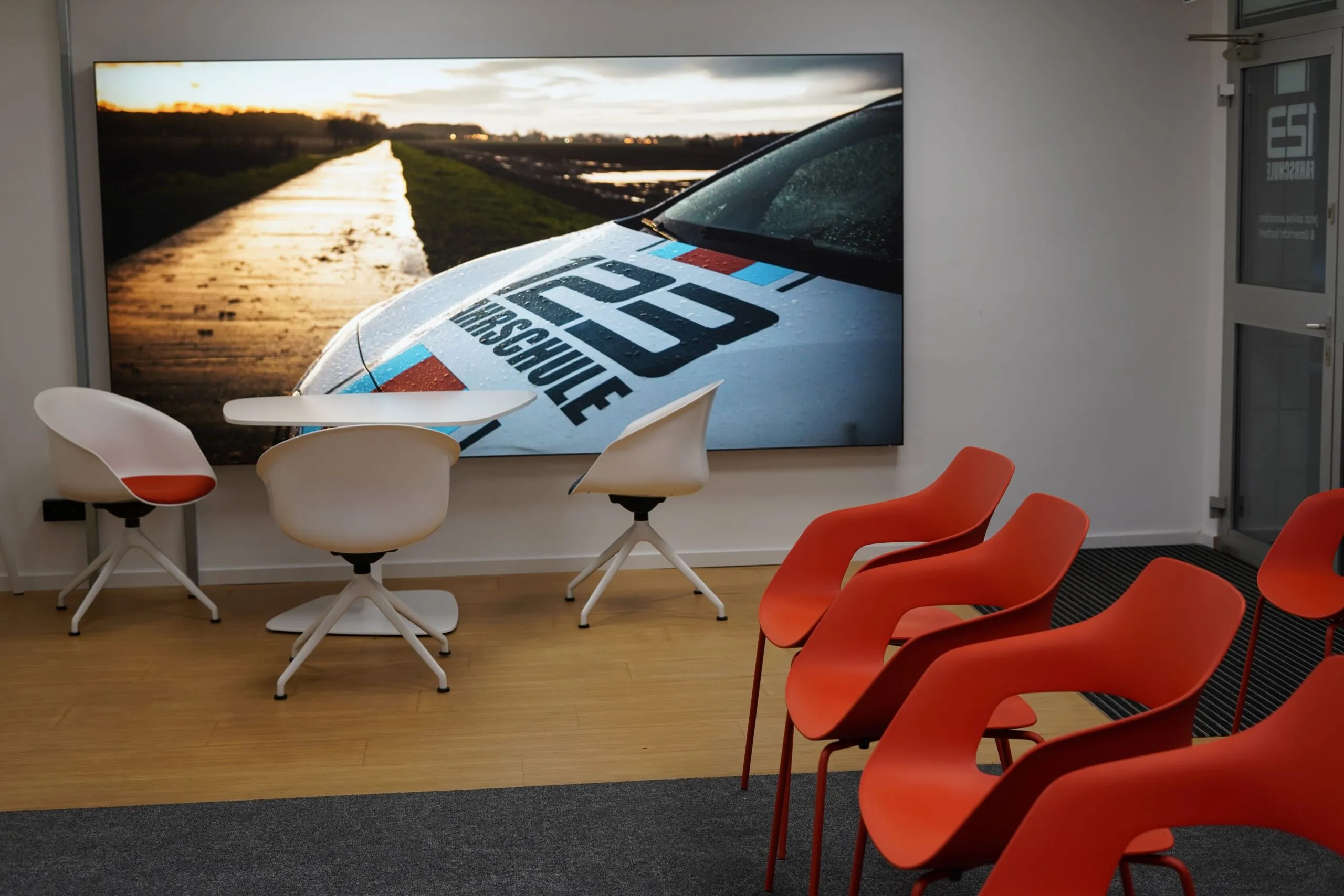 Raum für den Theorieunterricht mit großem Bild an der Wand von einem Auto mit der Aufschrift 123Fahrschule
