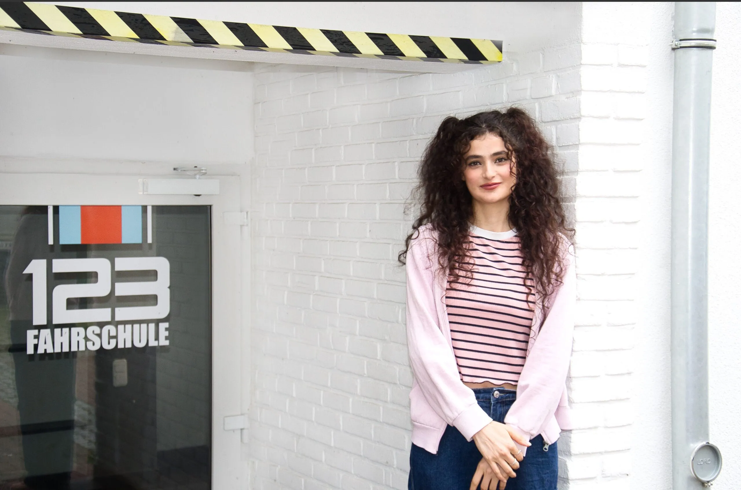 Schülerin steht vor einer Filiale der 123 Fahrschule