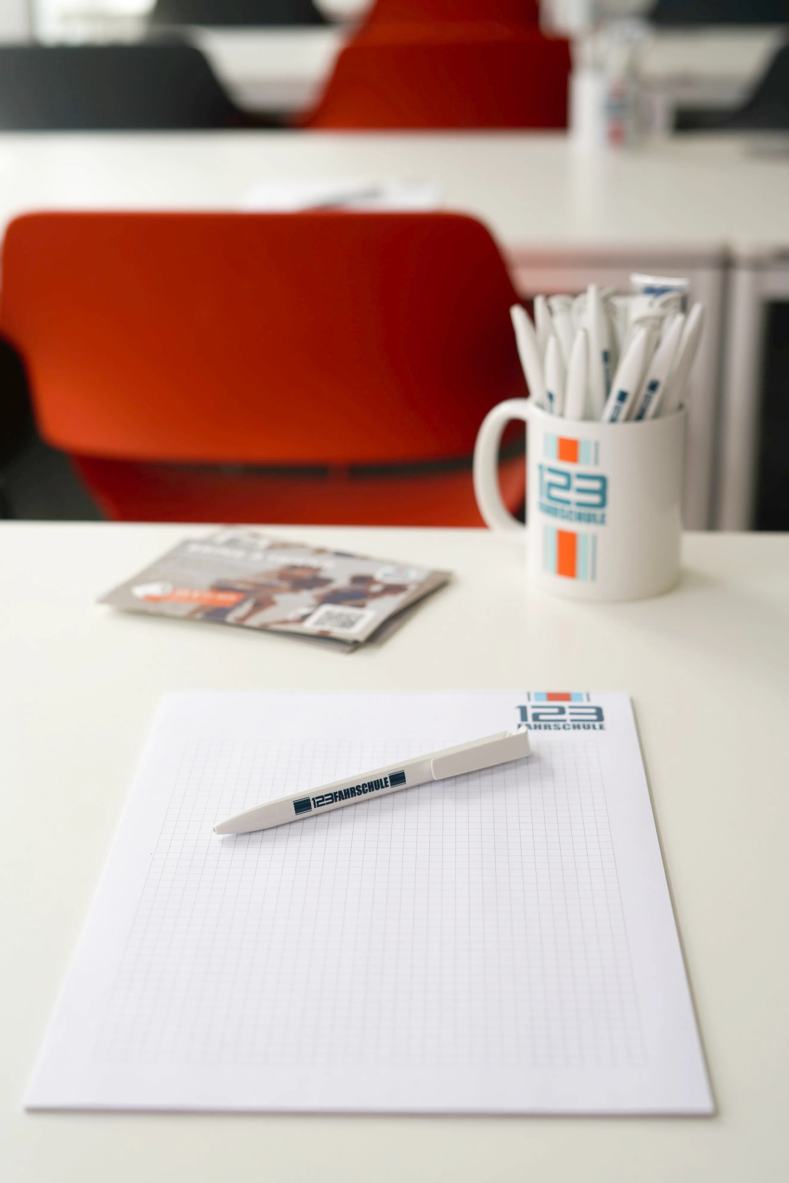 Utensilien, wie eine Tasse, ein Block und ein Stift einer Fahrschule liegen auf einem Tisch